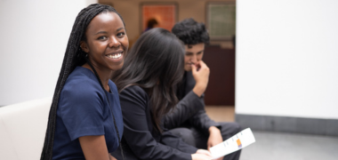 A woman smiling at the camera while other people talk in the background