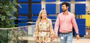 A woman and man walking together through an office