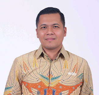 Individual wearing a patterned batik-style shirt with a BD logo pin, photographed against a plain white background in a portrait-style image.