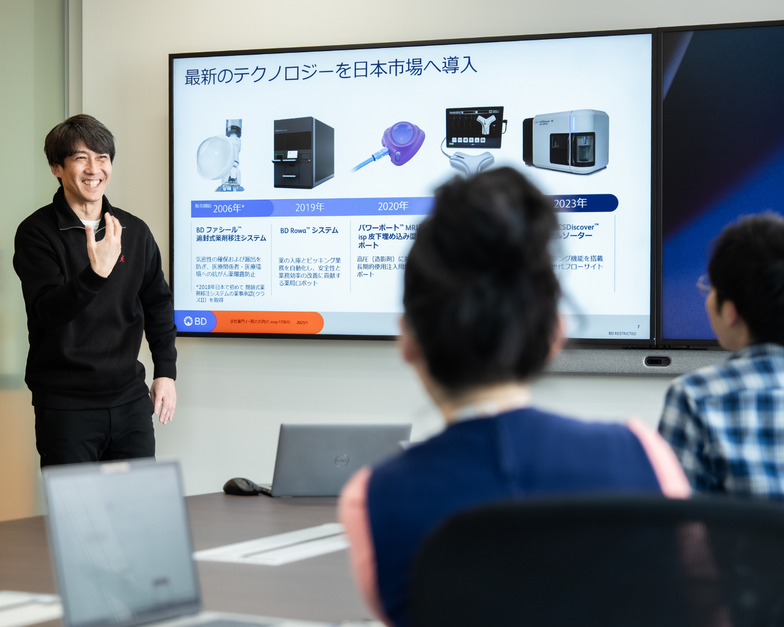 会議室で大型スクリーンを使い、日本市場向けの内容を説明している様子。
