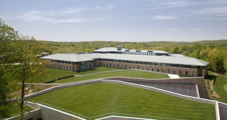 緑に囲まれた敷地内にある低層のオフィス施設を上空から見た外観。