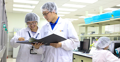 試験管を持った一人が笑顔を見せるエンジニアたち