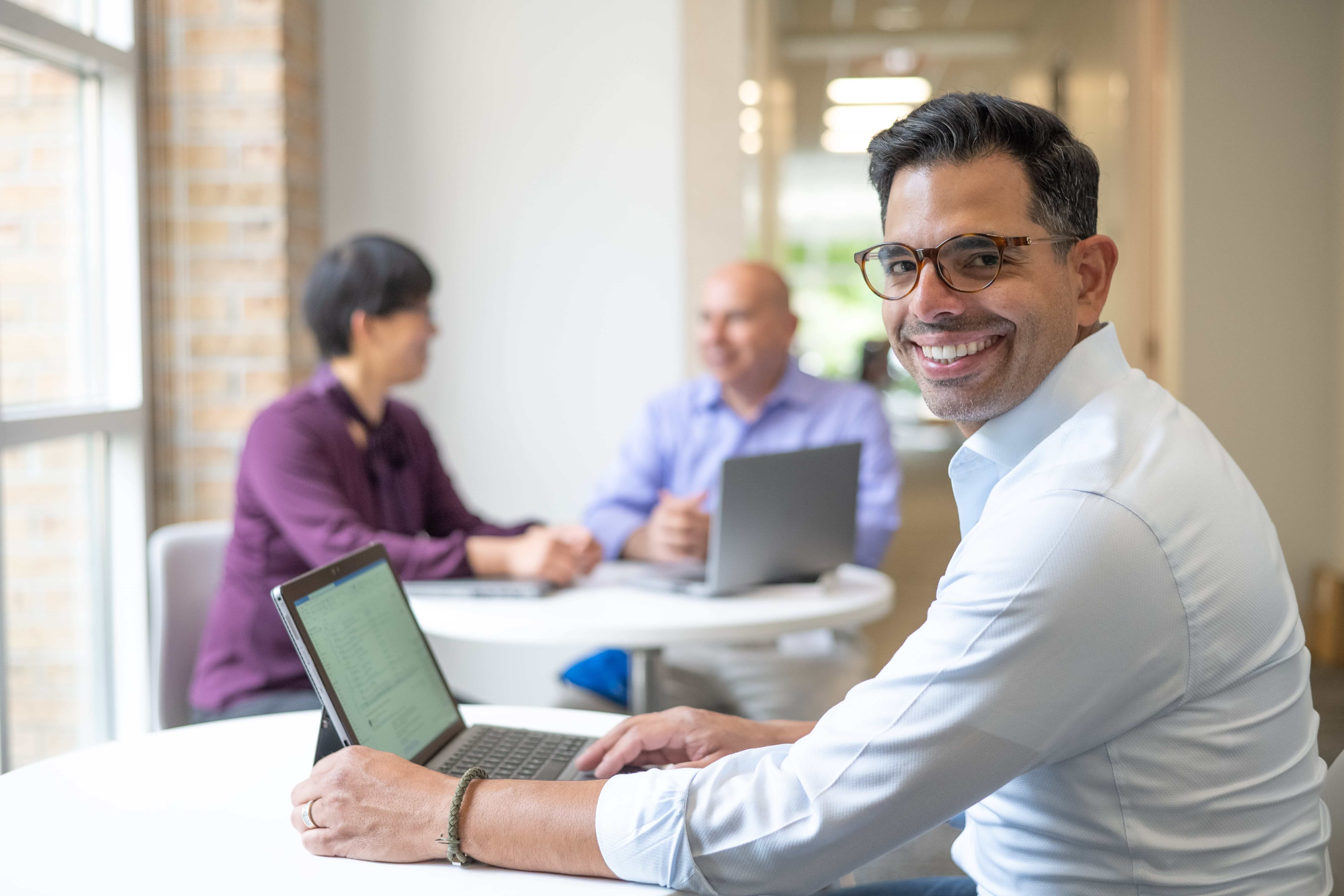 Man smiling at the camera while working in a group setting