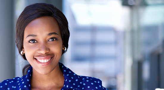 Black woman with dark short cropped hair smiling wearing polka dot blouse