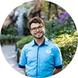 young male employee in a Disney parks uniform smiling for a photo outdoors