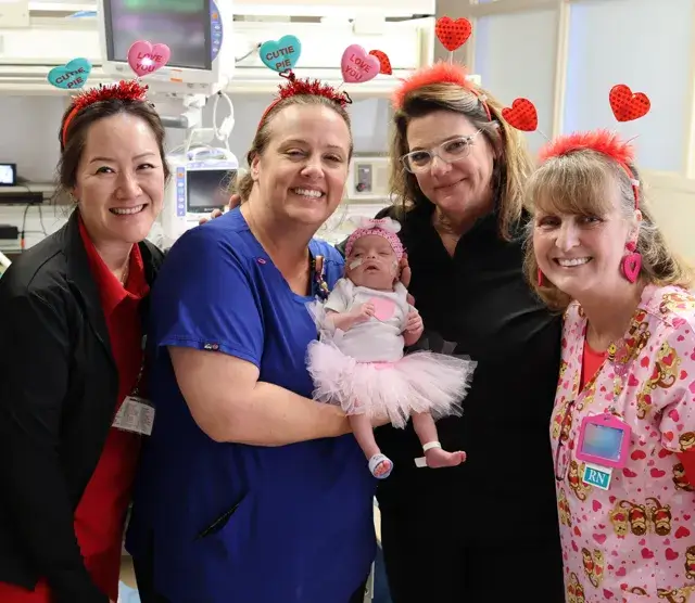 group of nurses holding a baby