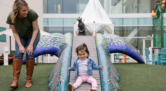 Little girl on slide - mother watching y