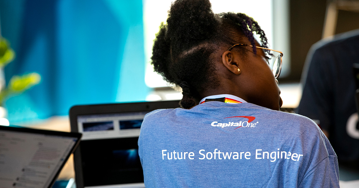 Woman with Future Software Engineer at Capital One shirt sits with her back facing, representing how Blacks in Tech at Capital One creates an inclusive community of technologists to help associates grow and thrive