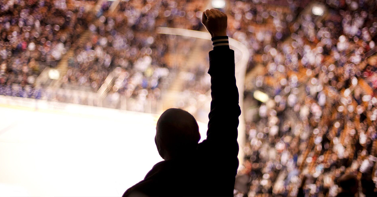 Silhouette of a man standing in a full arena with his fist in the air Capital One