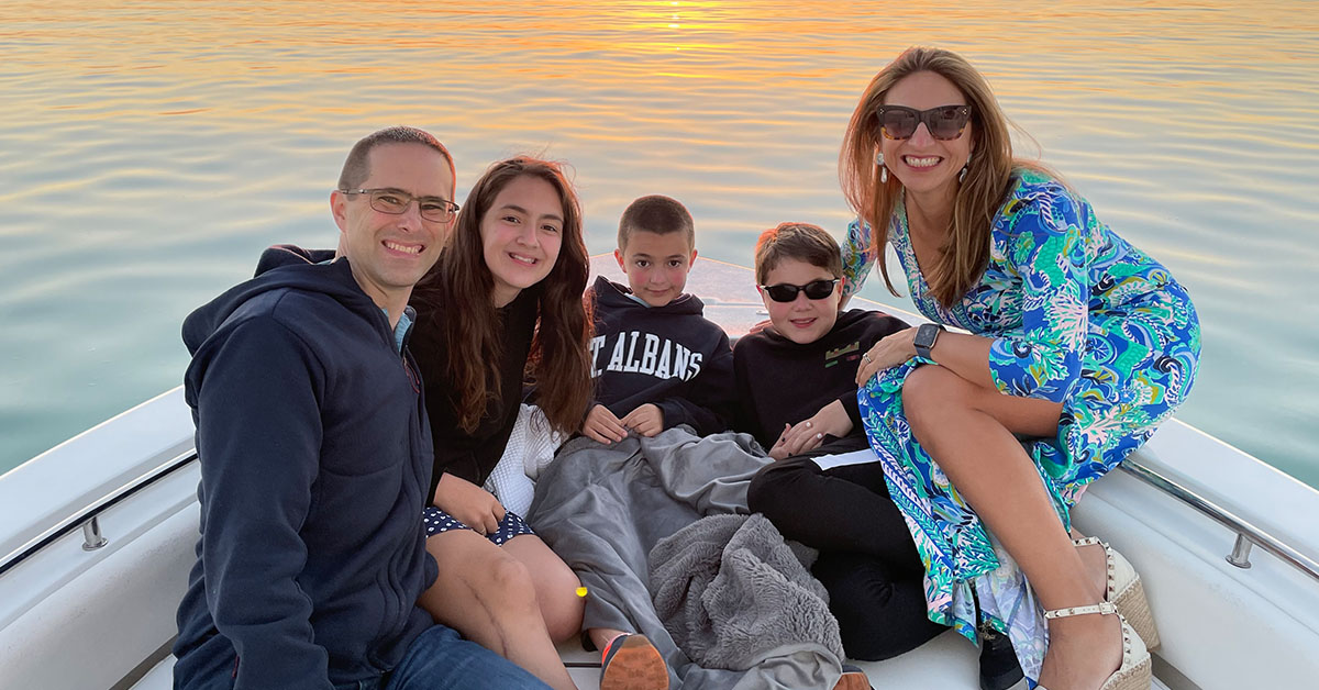 Cinthia Lopez, Capital One VP of Students and Grads Recruiting and Programs, sits in a boat on the water at sunset with her family