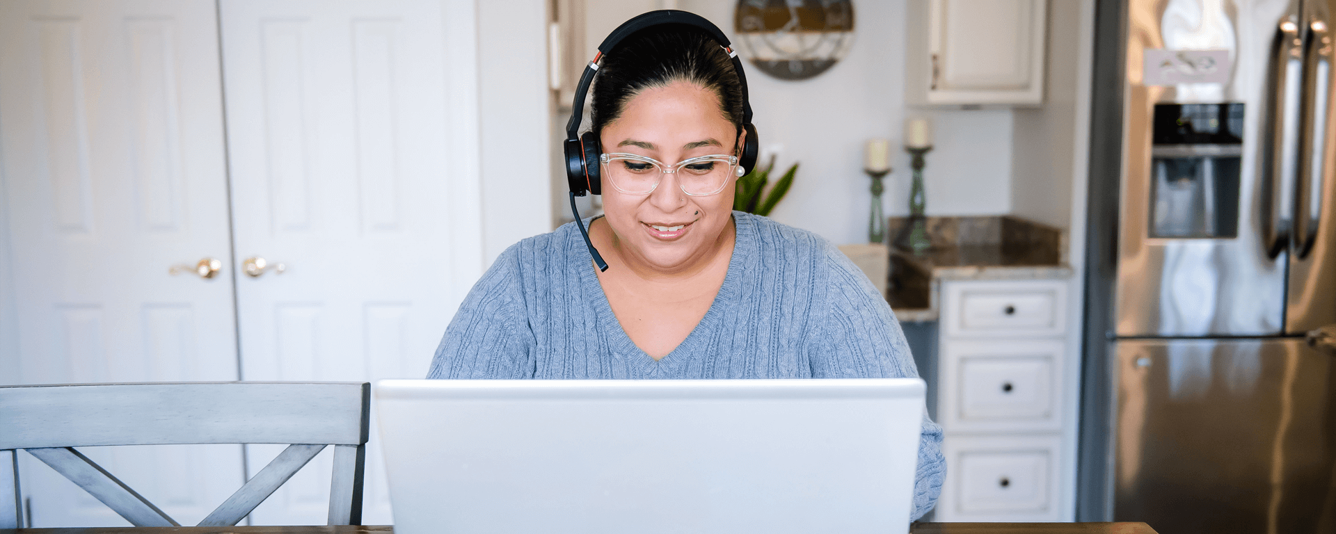 Capital One associate sits at her kitchen table and works from home wearing a headset