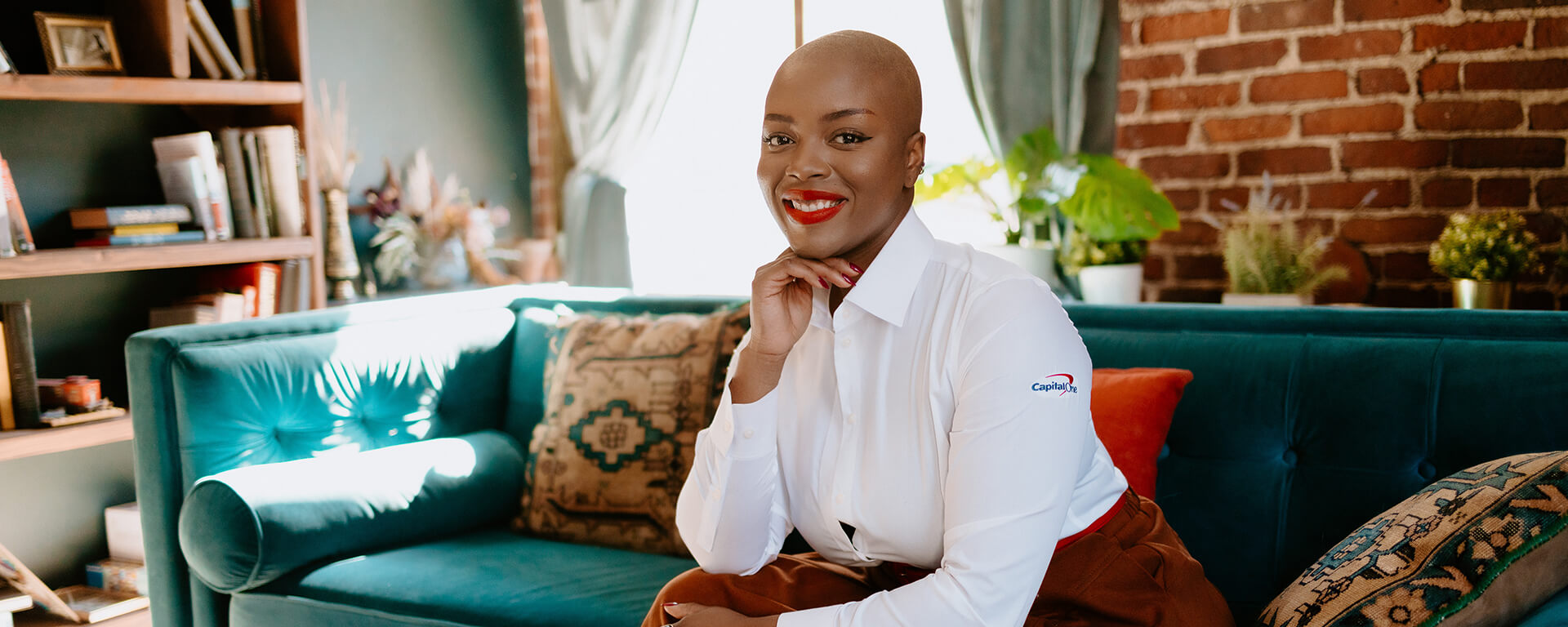 Capital One Cafe Ambassador BJ sits on her green couch