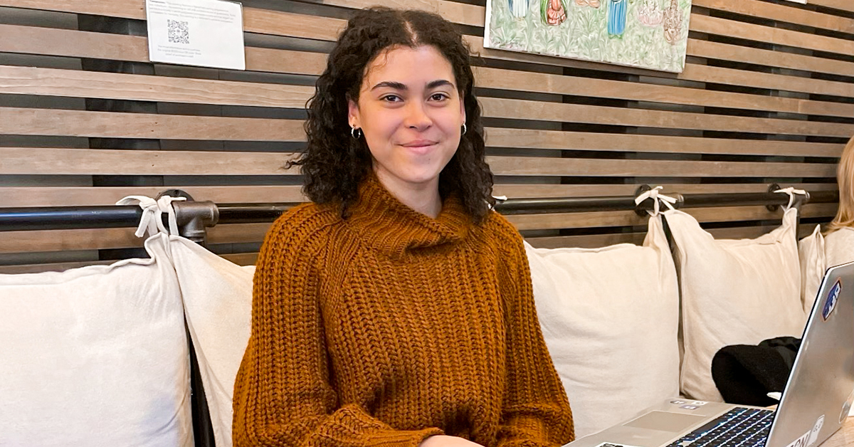 Kristina, Capital One Cyber Security Intern, sits on a couch with her laptop