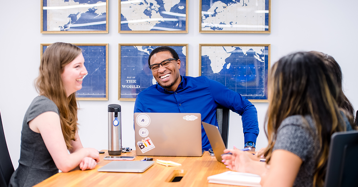 Capital One associates sit around a table with their laptops and collaborate