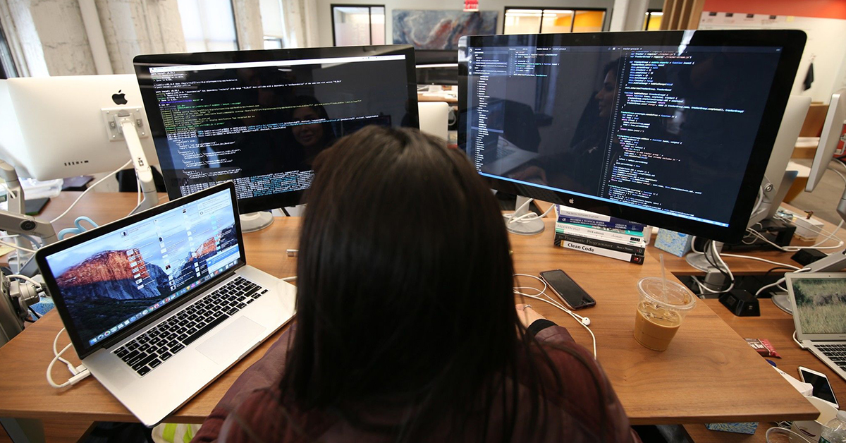 Capital One STEM associate working at her desk with multiple screens showing coding