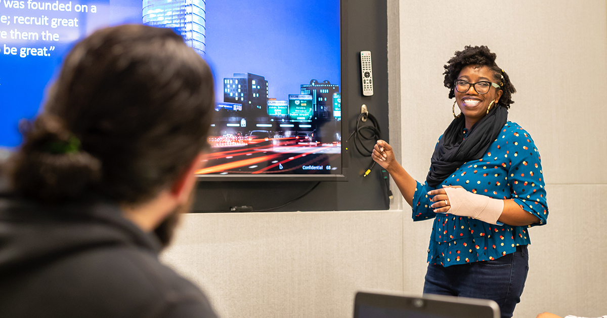 Capital One associate Joy stands in front of a projector screen and gives a presentation