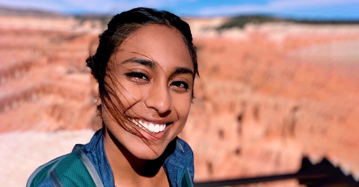 Mahi, Capital One associate, stands outside and smiles with the background of a blurry canyon