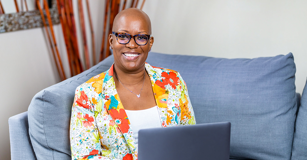 Capital One associate Michelle sits on her couch with her laptop 