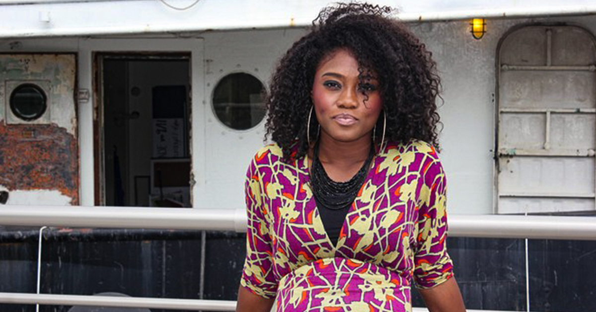 Vee, a Capital One associate, stands outside in front of a boat