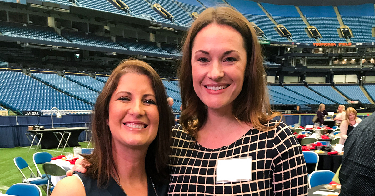 Two Capital One associates standing in an arena at a conference