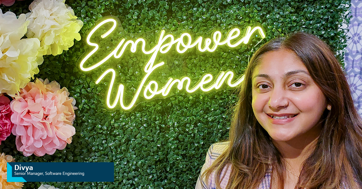 Capital One associate Divya, Software Engineer Senior Manager, sits in front of greenery wall with a neon sign that says 