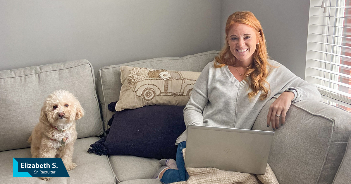 Liz, Capital One Senior Associate, Tech Recruiting, sits on her couch with her laptop with her little white dog