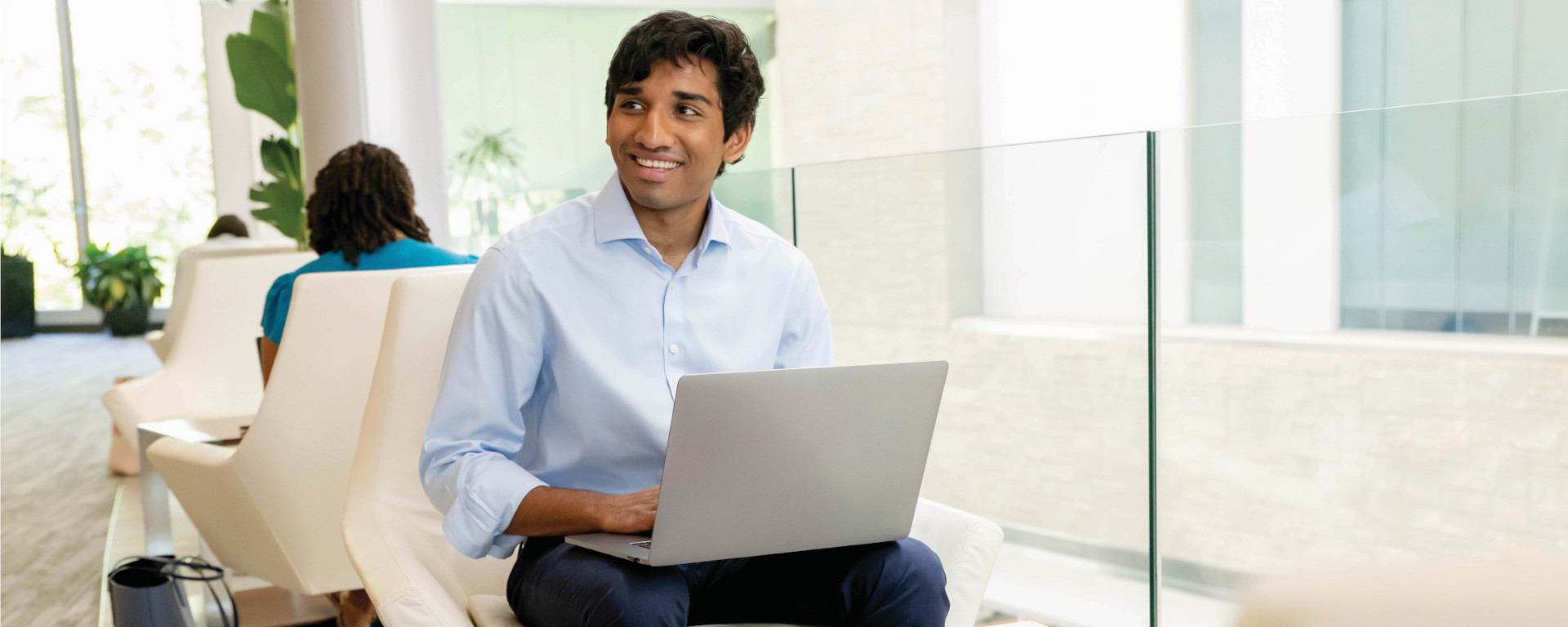 Capital One student and grad associate sits in a chair in front of a stairwell at a Capital One office and talks about his internship experience