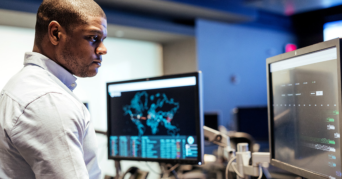 Man stands at computers in Capital One, representing how Blacks in Tech at Capital One creates an inclusive community of technologists to help associates grow and thrive