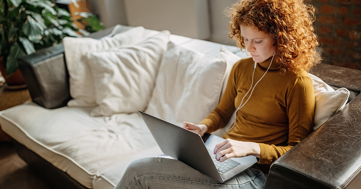 Woman sits on couch and works from home for Capital One