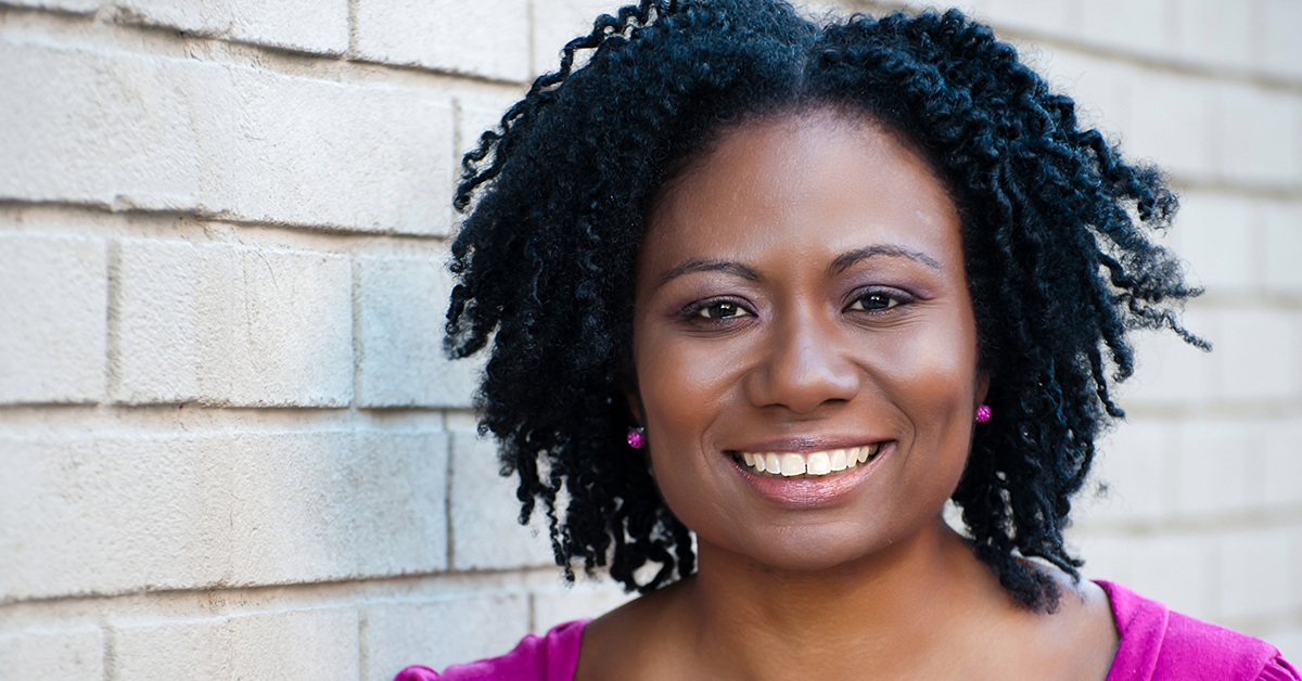 Jamillah, a director at Capital One, stands in front of a green background