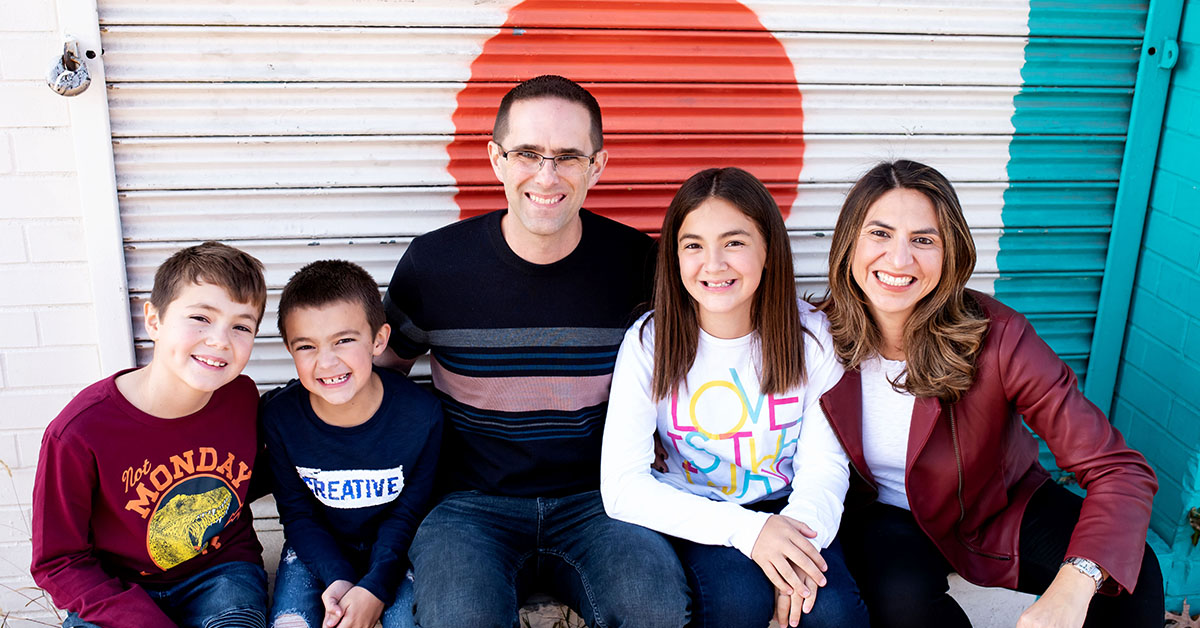 Cinthia Lopez, Capital One VP of Students and Grads Recruiting and Programs, sits in front of a storage unit door with her husband and 3 children, and talks about her experiences as an immigrant and in leadership