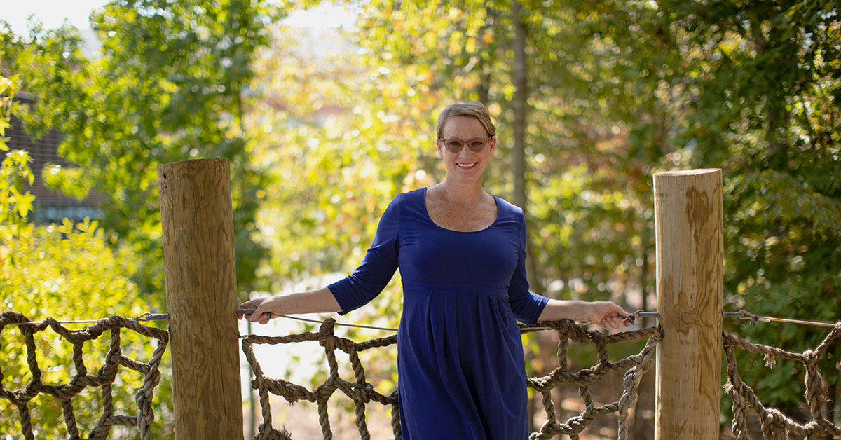 woman smiling in a treehouse in front of a forest