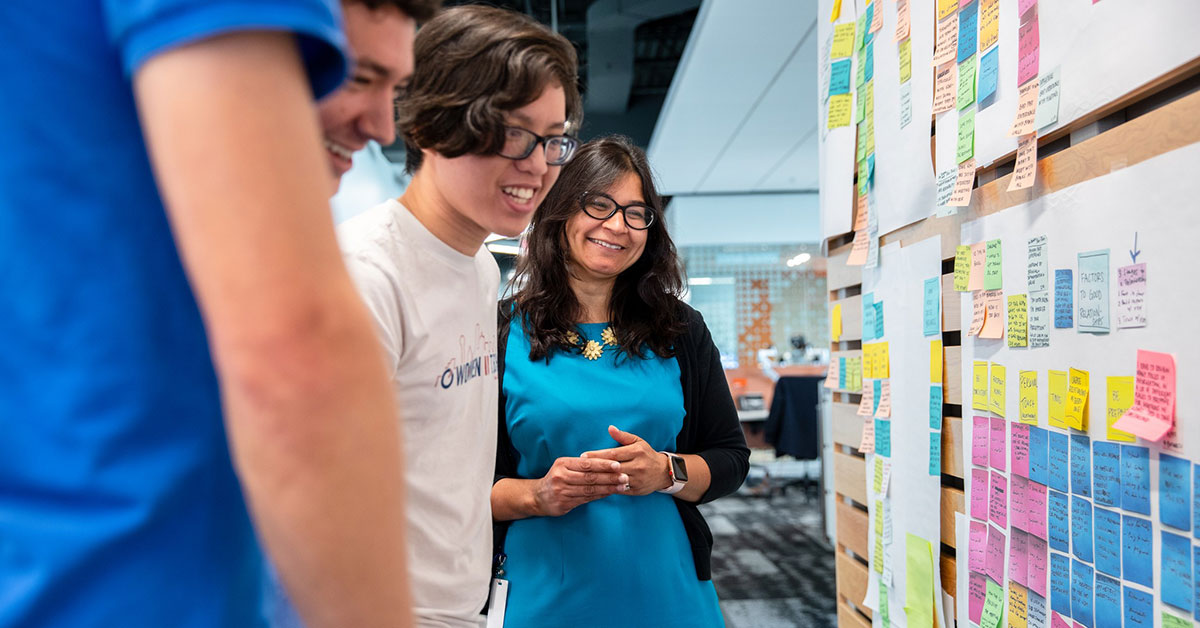 woman working with young men at design thinking board