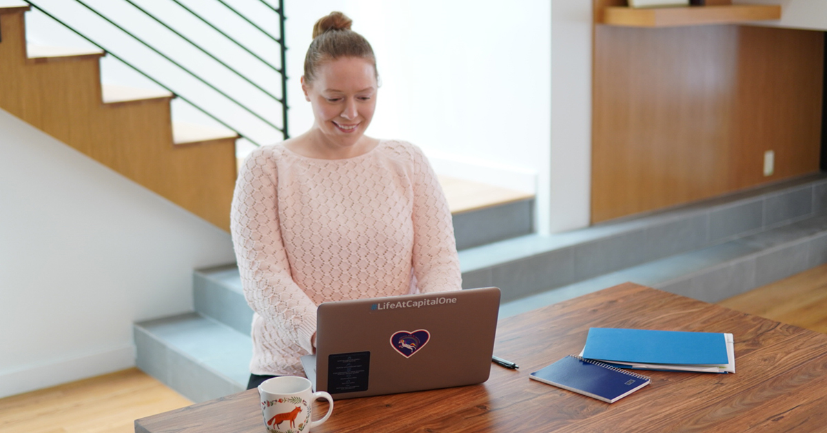 Capital One associate stands at her laptop and learns how to work effectively from home