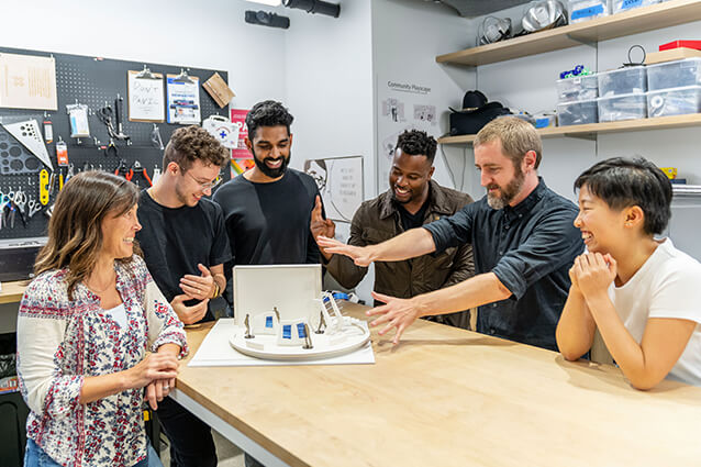 Group of employees standing around a tabletop diagram of a retail space.