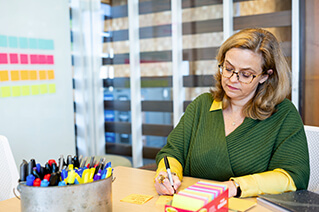 Employee making notes at a table using different colored markers.