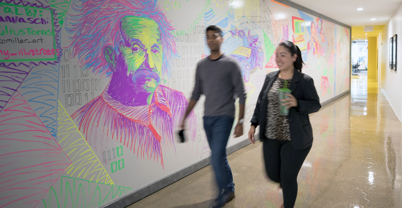 Employees walking down hallway with painted mural
