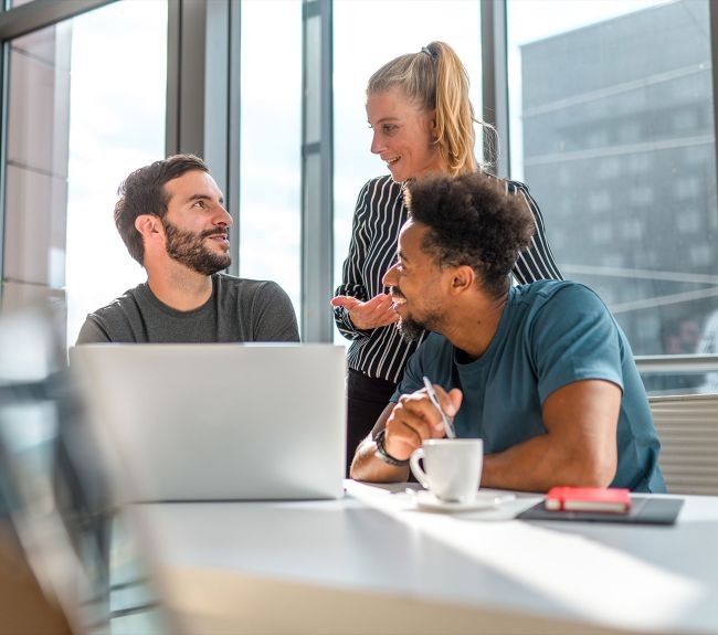 3 coworkers talking over a laptop