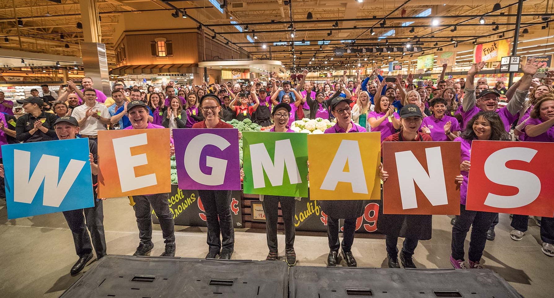 Wegmans employees lined up holding sign that says Wegmans