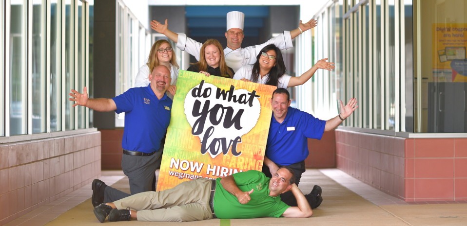Wegmans employees smiling and holding a poster that says Do What You Love