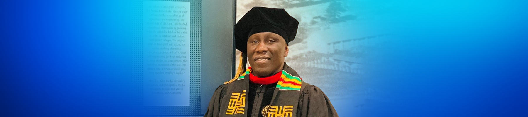 Photo of Nixon Opondo wearing his graduate gown, facing the camera and smiling 