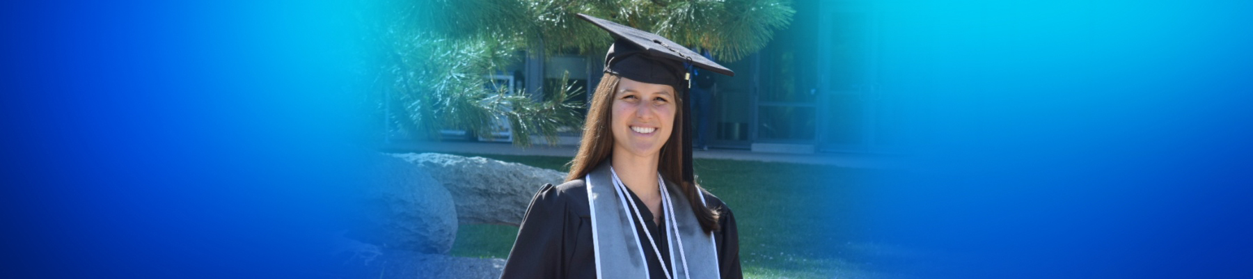 Photo of Lisa wearing a graduate gown, facing the camera and smiling 