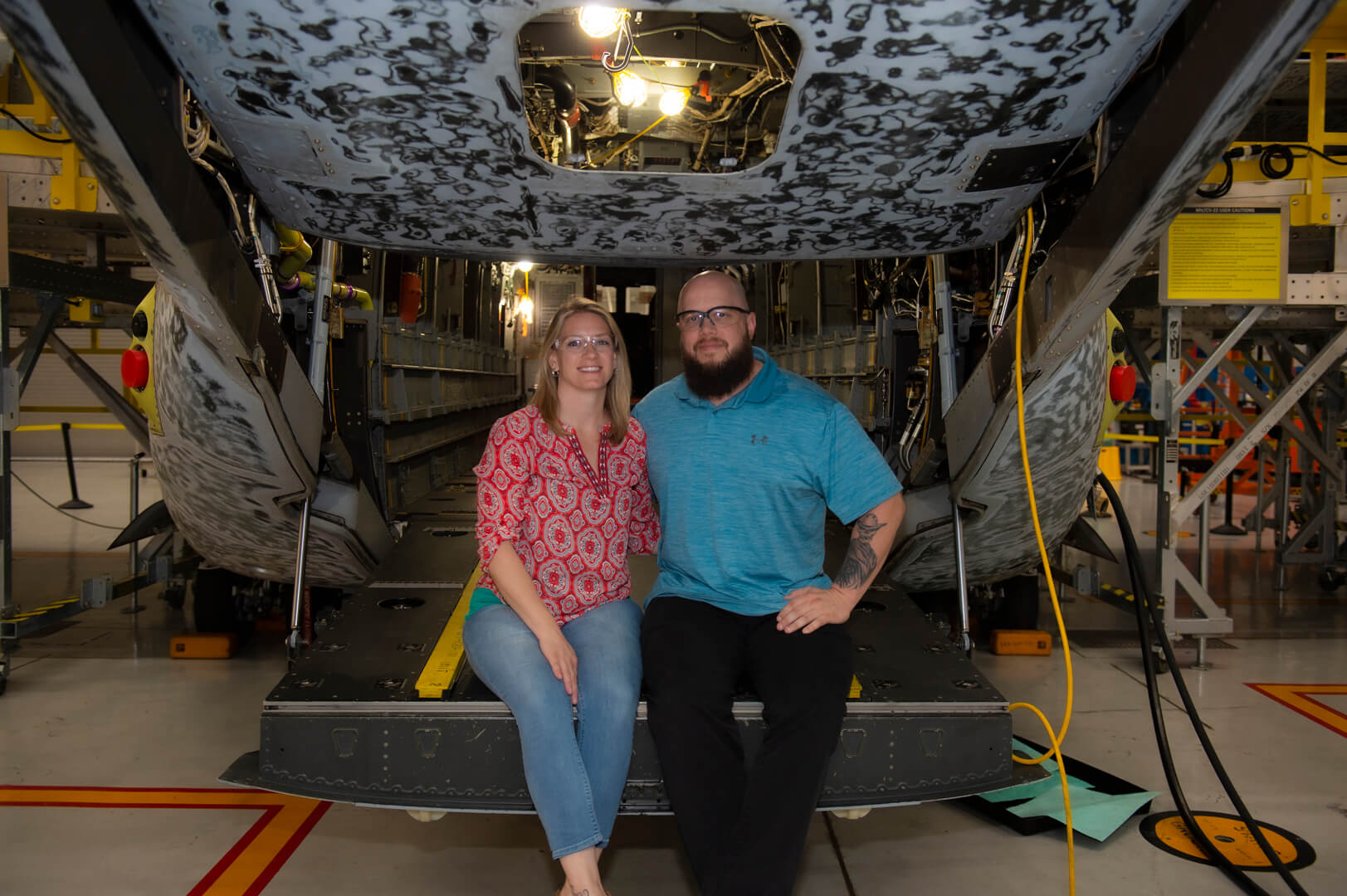 Melissa and Derek Carpenter sitting on the hatch of an MV-22 Osprey