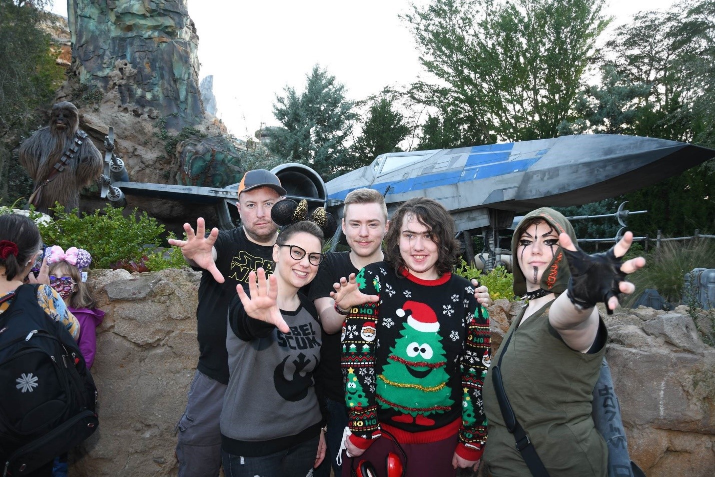 Elizabeth and her family are standing outside the Star Wars attraction with outstretched arms, using the force. 