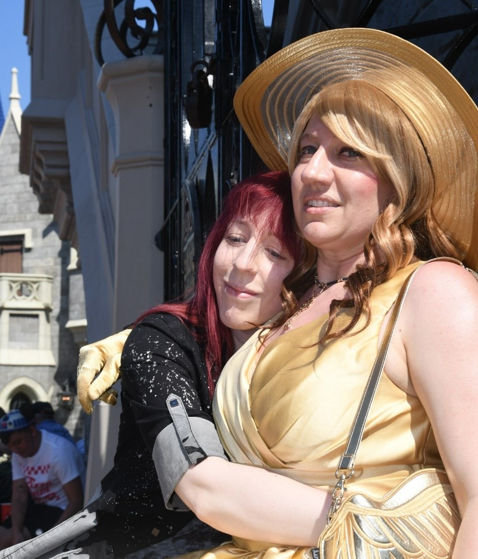 Maggie is being embraced by her partner Ryn at Disney World.  