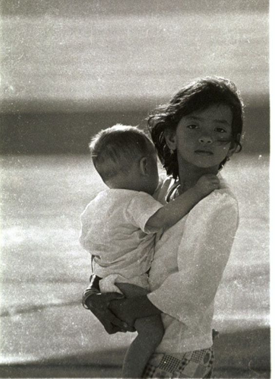 Black and white image of Teresa as a child, holding her baby brother in her arms.