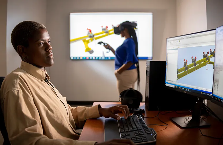 black employee sitting at a computer desk and designing a 3D model