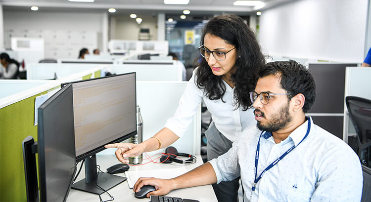 Indian male and Indian female employee looking at a computer screen in an office cubicle