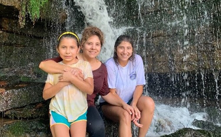 Marcela, her mom and her sister in front of a water fall.