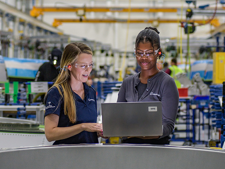 Female employees wearing safety goggles and looking at a computer